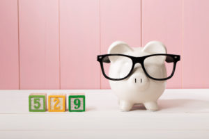 529 college savings plan theme with white piggy bank with Eyeglasses on pink wooden wall